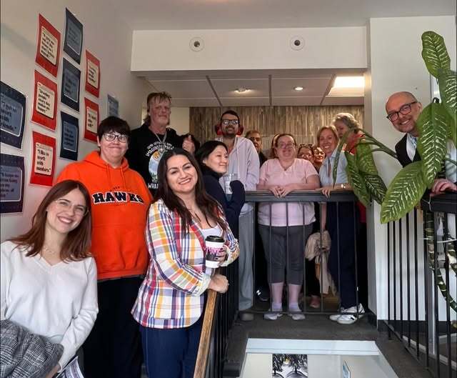 District 6 staff and Heather smile while standing on a staircase alongside Vail members.