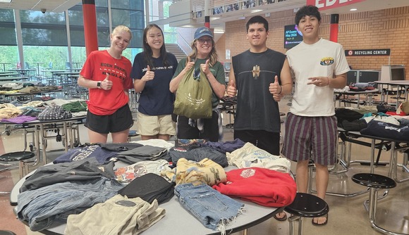 Students posing at a clothing swap in their cafeteria