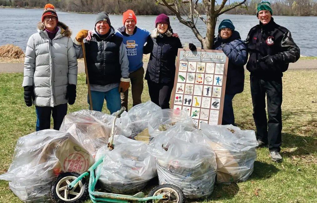 Group of people smile in front of a pile of waste collected.