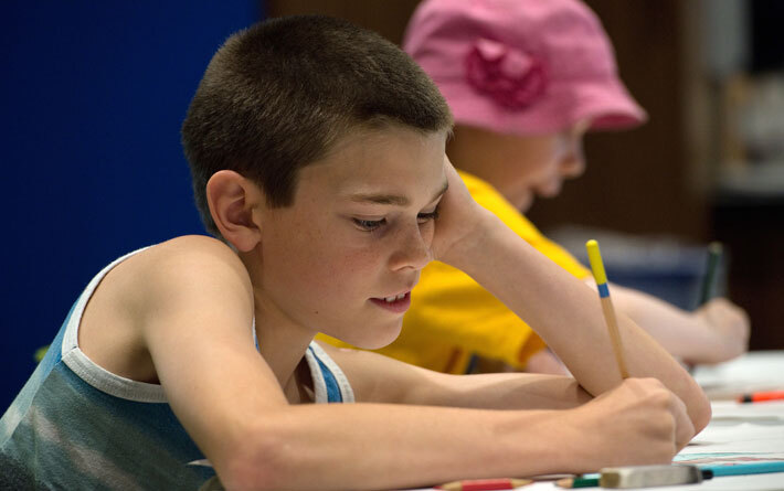 child using a pencil at a table