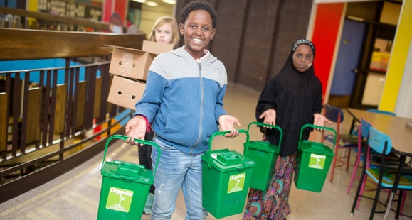Students in a school hallway carrying countertop organics bins