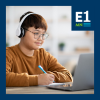 Teenage boy does work on his laptop, the E1MN logo is in the top corner