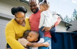 Family hugging outside a garage door
