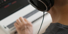 Person using a refreshable braille display, headphones, and a laptop.
