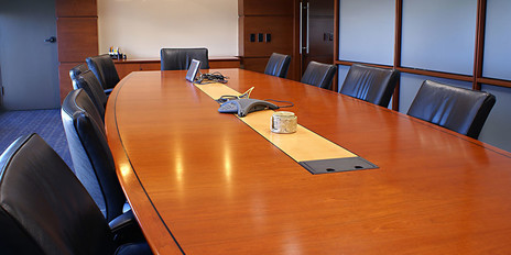 Conference room with large, formal table, chairs, and conference phone.