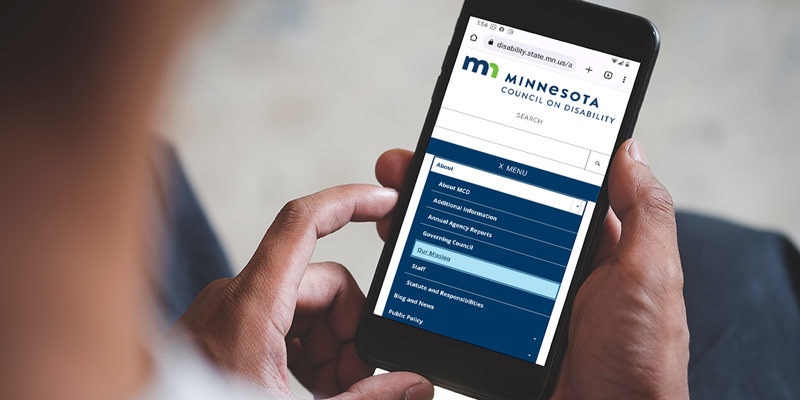 Hand holding smartphone. Onscreen: Minnesota Council on Disability website.