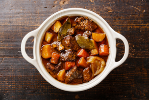 Overhead photo of stew in a white bowl on a wood table.