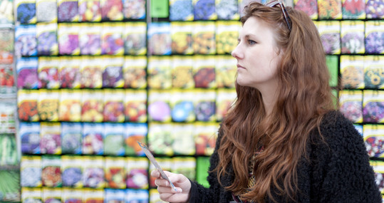 Woman looking at a seed packet in a retail store. 