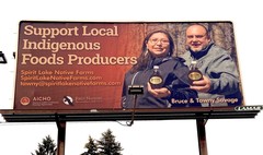 Picture of a billboard that says "Support Local Indigenous Foods Producers" and a photo of  Bruce and Tawny Savage of Spirit Lake Native Farms