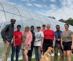 Village Agricultural Coop: A group of people in front of a high tunnel hoop house.