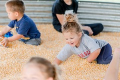 Children around 5 years old playing in a grain bin corn pit.