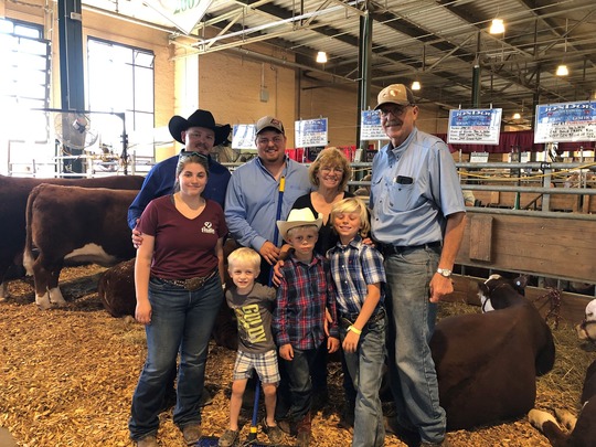 The Pettit Family gathered in front of their Hereford cattle at a fair.