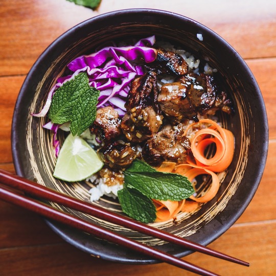 A photograph of a bowl of hearty beef soup with cabbage and carrots.