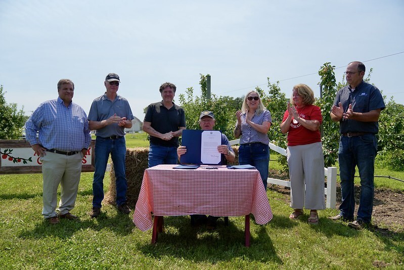 Governor holding signed bill flanked by people on both sides