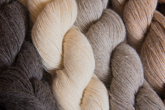 four skeins of yarn blending from a midtone brown to cream