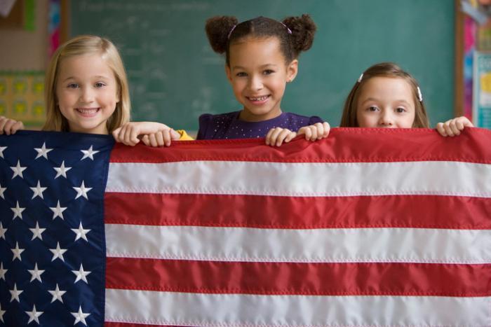 three diverse young women holding US flag