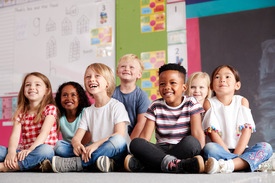 A group of diverse children sitting next to each other and smiling