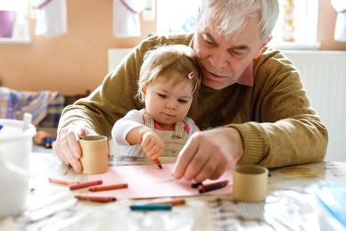 Grandfather helping grandchild color with crayons