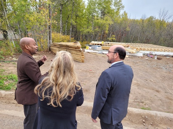 Commissioner Willie Jett speaks with a man and a woman at the construction site of a house 