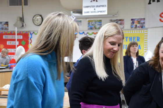 Patty Hand watches something happening off camera while a student looks at her. 