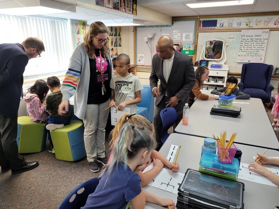 Commissioner Willie Jett bends down to speak with a child during a visit to the classroom