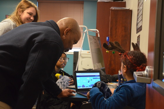 Commissioner Jett leans down to speak with students working at computers 