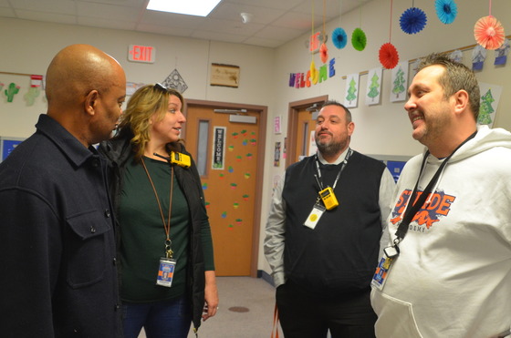 Commissioner Jett speaks with two men and a woman in a school hallway