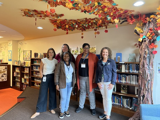 Sonia Smith and Katona Barnes stand in a school library with three other women