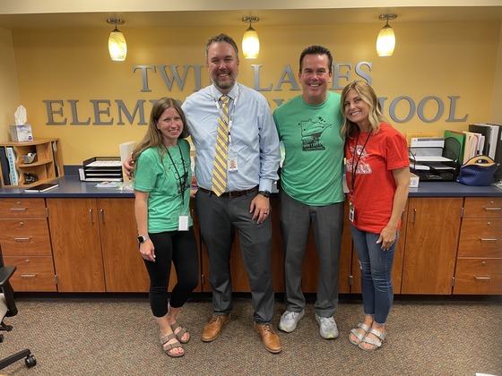 Assistant Commissioner Daron Korte stands with three people in front of a sign that says Twin Lakes Elementary School