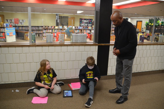 Commissioner Jett speaks to two students working in the hallway outside a library