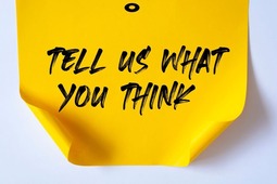 Image of yellow post it note that says tell us what you think