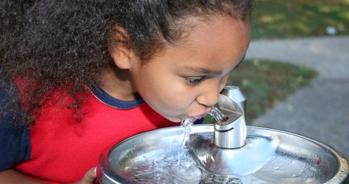 girl drinking from outdoor water fountain