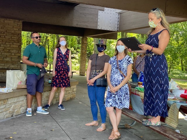 one man and three women standing in a picnic pavillion