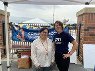 Two people standing in front of State of Minnesota COVID-19 Vaccines banner