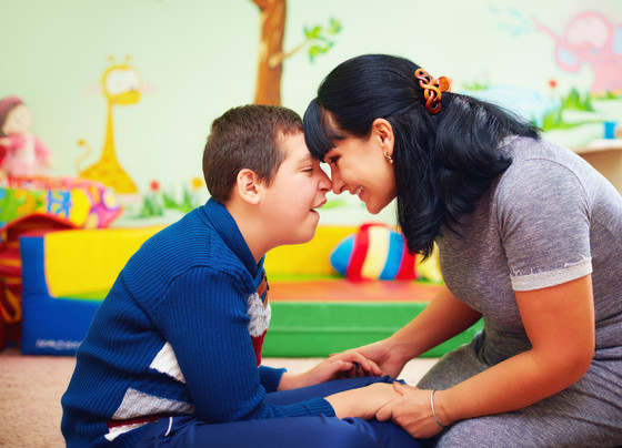 adult and child sitting in colorful room with heads touching