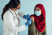 Medical professional applying band-aid to person's shoulder after vaccine