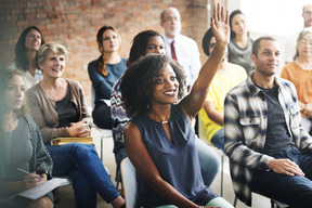 Group of people seated with woman raising hand