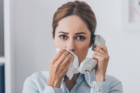 person on phone blowing nose