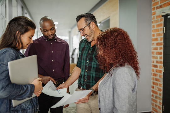 People standing together and discussing papers