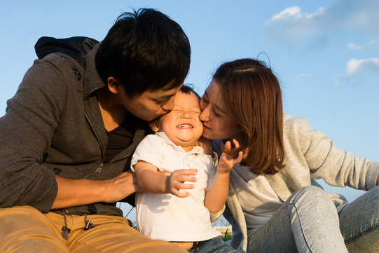 woman and dad kissing toddler 