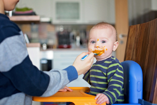 toddler eating baby foods in highchair