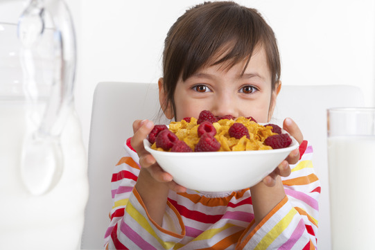 child with bowl of cereal with berries
