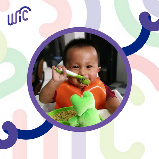 infant at table feeding self