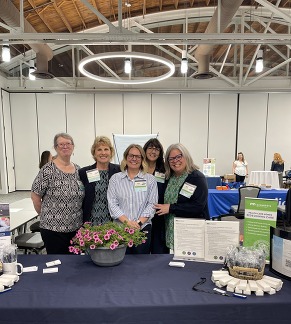 Five Health Care Homes Learning days Team members standing behind a booth with a blue table cloth