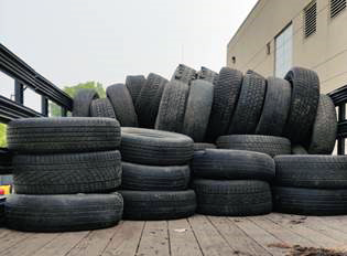 Pile if worn car tires in back of open air truck.