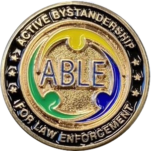 Gold circular pin with raised text "Active Bystandership For Law Enforcement ABLE"