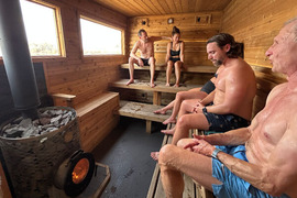 People seated inside wooden sauna with fire glowing