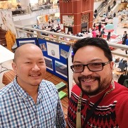 Two men smiling in front of a display table.