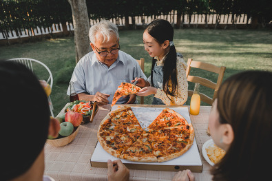 Multigenerational Asian family eating pizza outside