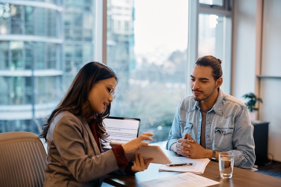 Woman taking to man sitting at desk